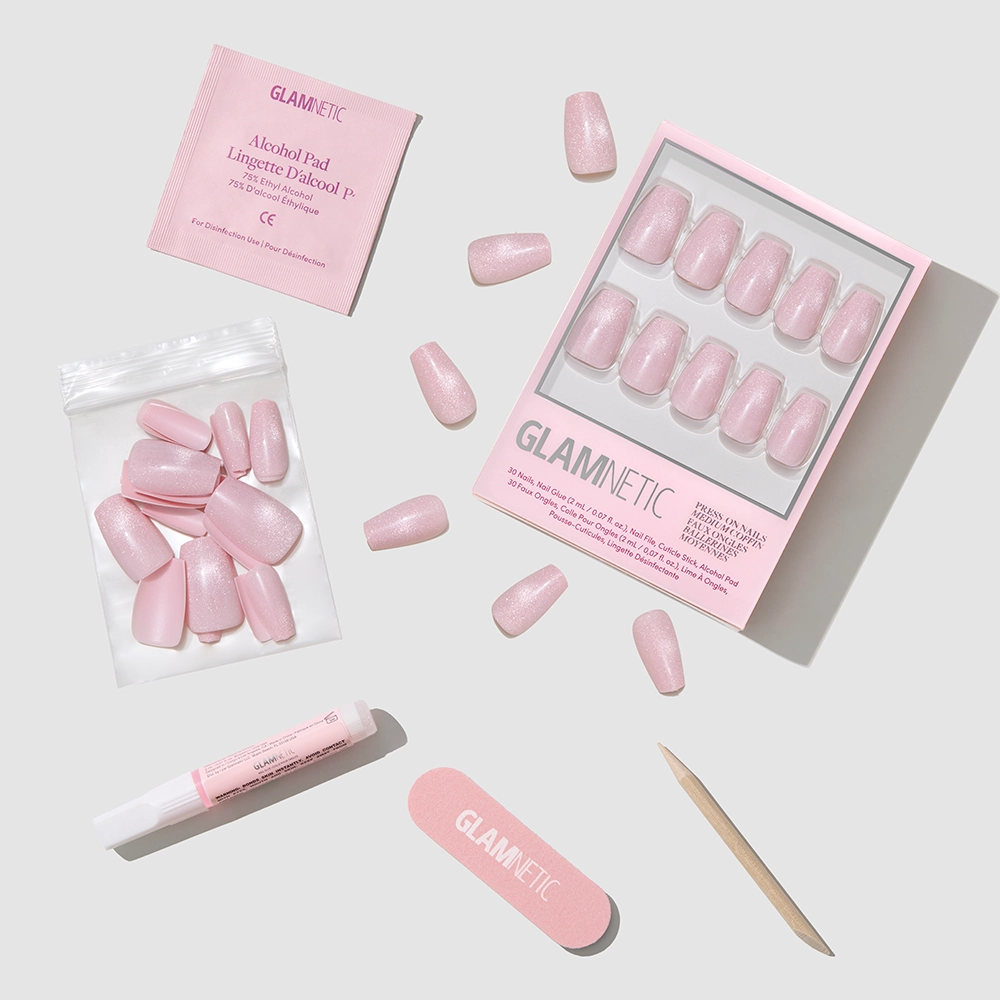 The glamnetic Pink Secret coffin press-on nail kit includes shimmering, salon-quality nails, glue, file, wooden cuticle stick, alcohol pad, and extra nails—all displayed on a light gray background.