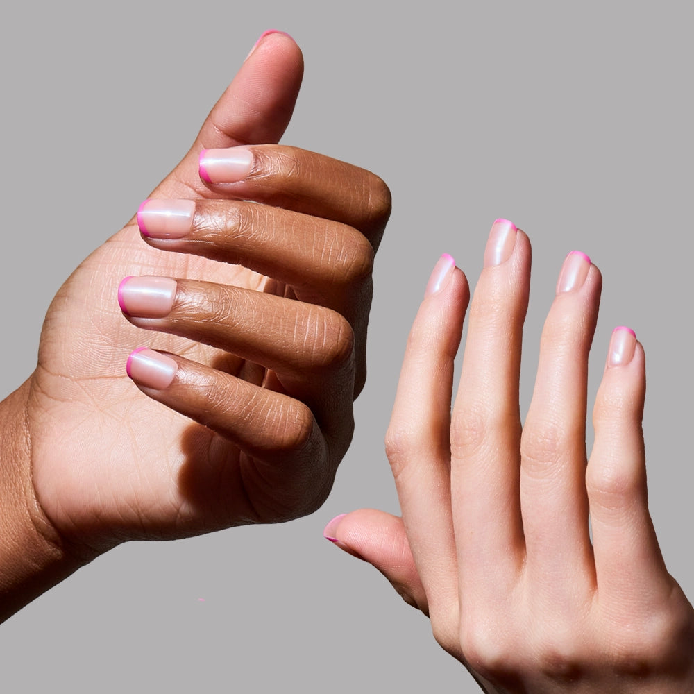 Two hands with different skin tones display glamnetic’s Pink Tutu micro-French tips against a plain grey background. Nails are well-groomed with a soft, glossy finish; the hands are open and fingers slightly spread. - Product image