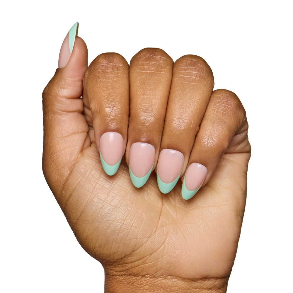 A hand with medium brown skin showcases salon-quality nails created with glamnetics Pistachio Crème, a chic nude base paired with light green French tips, set against a white background. - Product image
