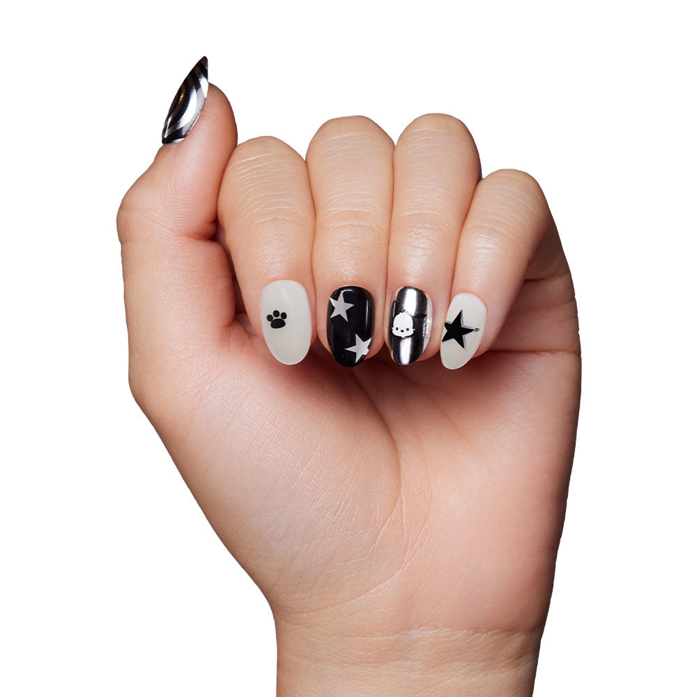 A hand with manicured press-on nails featuring black and white designs—paw print, stars, skull, and solids—captures the playful style of the Pochacco™ Nail Set from the Sanrio collaboration. - Product image