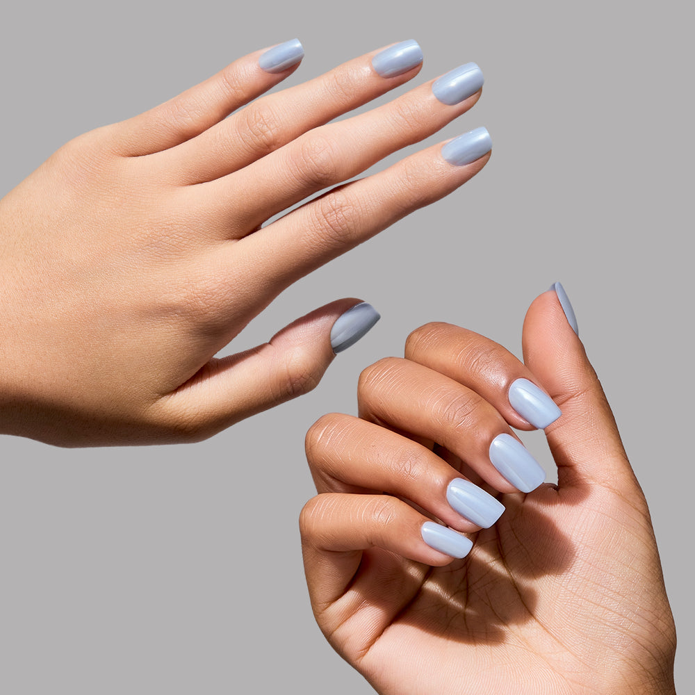 Two hands with short squoval press-on nails painted in a glossy light gray polish are displayed against a plain gray background, evoking the chic style of glamnetic's Powder Bleu Press-On Nails. - Product image