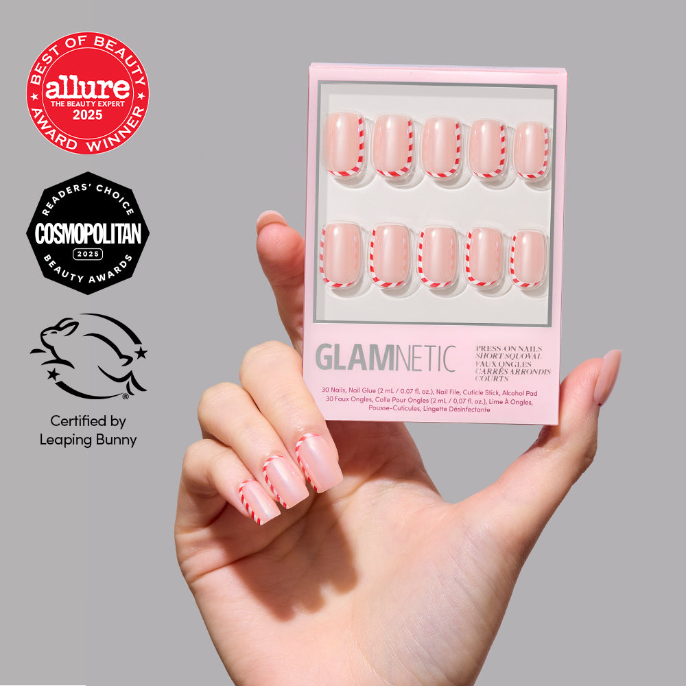 Pretty in Peppermint - A hand holds a box of Glamnetic Pretty in Peppermint short square holiday press-on nails featuring a clear base with red and white peppermint-striped tips.