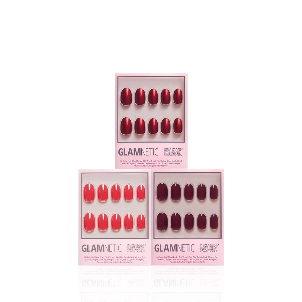 Three boxes of glamnetic’s Round in Red salon-quality mani press-on nails are displayed against a white background. Each box contains ten red and pink press-on nails in assorted shades, neatly organized in rows. The packaging features a soft pink border. - Product image