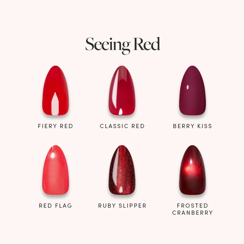Six glamnetic nail polish samples in shades of red are displayed on a light background under the title "Seeing Red." The shades—Fiery Red, Classic Red, Berry Kiss, Red Flag, Ruby Slipper, and Frosted Cranberry—are perfect for pairing with your favorite press-on nails or for creating a bold statement red look on short almond nails.