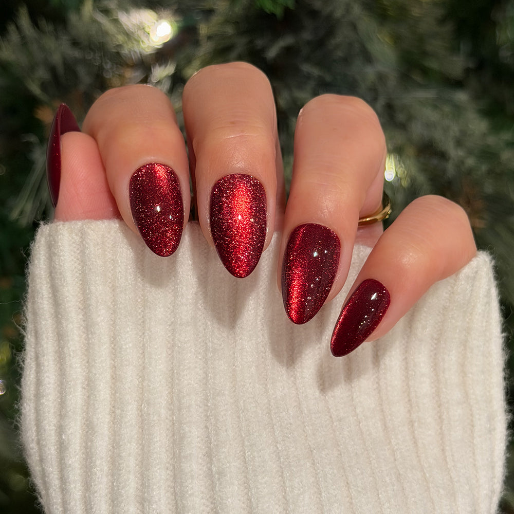 Ruby Slipper - Hand wearing short almond Glamnetic Ruby Slipper press-on nails with a shimmering red velvet finish.