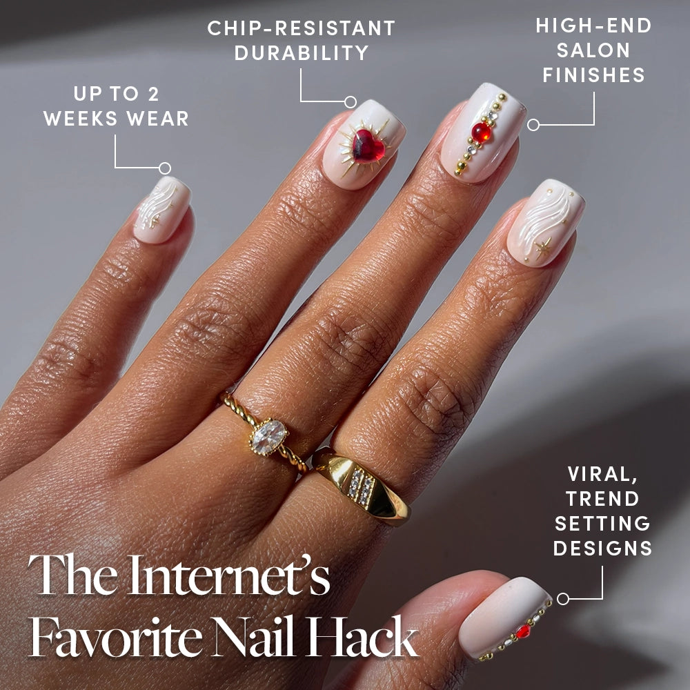 A hand with long, decorated nails featuring gold and red accents, adorned with gold rings. Text highlights the durability, salon-quality artistry, trendy designs, and up to 2 weeks of wear offered by glamnetic Ruby Press-On Nails. At the bottom, "The Internet’s Favorite Nail Hack" is written, showcasing the stunning effect of glamnetic's Ruby nails. - Product image