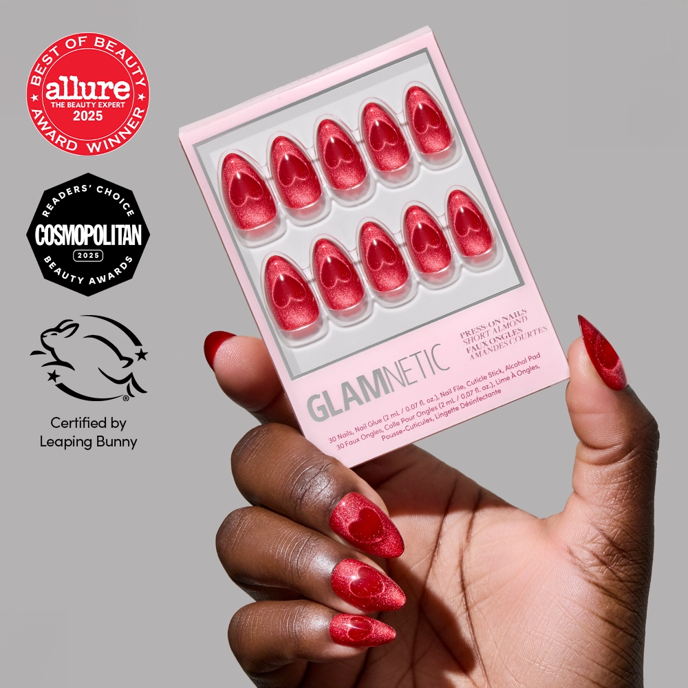 A hand with red velvet short almond Sent with Love press-on nails by glamnetic holds a matching box. Logos for Allure, Cosmopolitan, and Leaping Bunny awards and certifications are shown on the left side of the image.