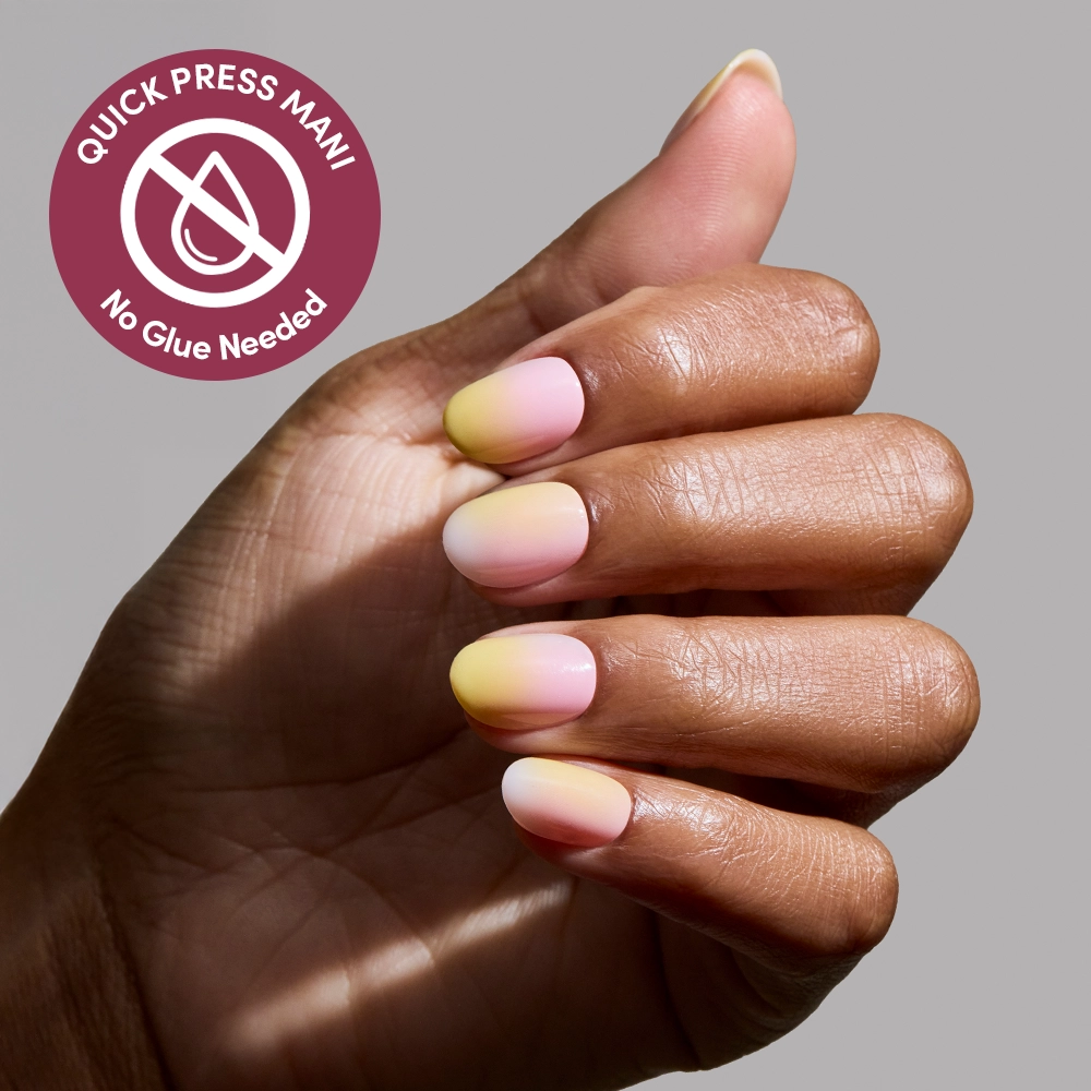 A hand with short, almond-shaped glamnetic Sherbert press-on nails shows a yellow-to-pink ombré manicure. A circular badge reads Quick Press Mani, No Glue Needed with a crossed-out glue drop icon. Background is light gray. - Product image