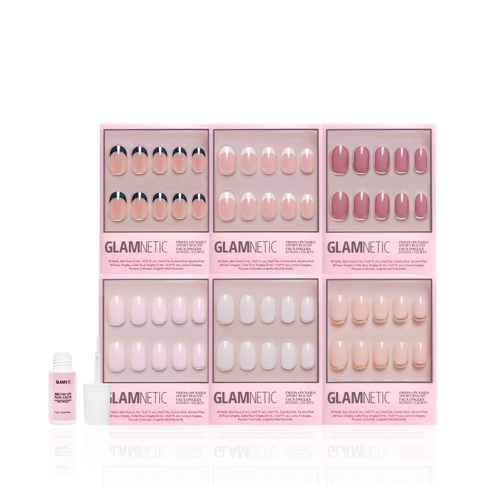 Six boxes of glamnetic Short Round Icons press-on nails are shown, featuring various nude and pink shades with milky finishes and French tips. A bottle of nail glue is on the left against a white background. - Product image