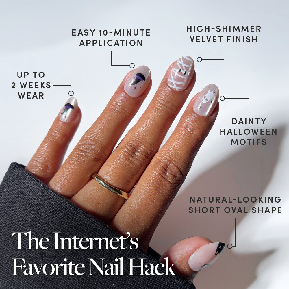 A hand displays the glamnetic Shriek Boutique press-on nails set in a short oval shape, featuring Halloween-themed dainty designs. The 10-minute application nails offer a high-shimmer finish and up to 2 weeks of wear. Text highlights these features against a white background. - Product image