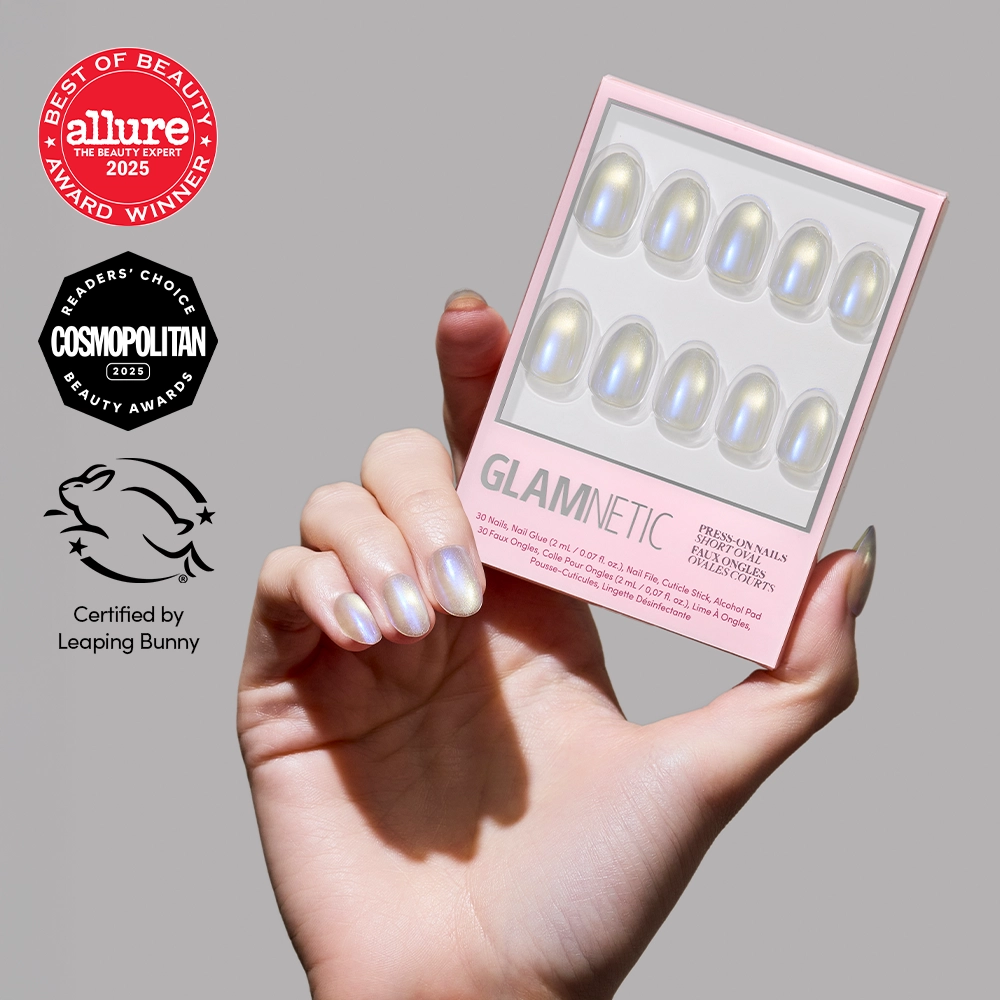 A hand with shiny, iridescent blue chrome Silver Siren press-on nails holds a pink glamnetic box. Beauty award badges from Allure, Cosmopolitan, and Leaping Bunny certification are shown on the left.
