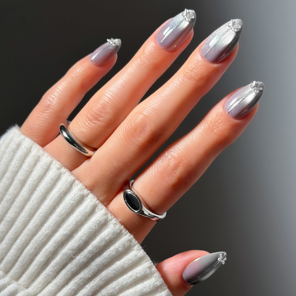 Silver Stockings glamnetic short almond nails with a silver metallic ombre finish and a small star charm at the base of each nail. - Product image