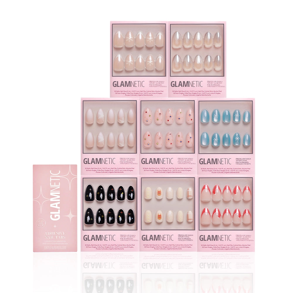 Nine sets from glamnetic’s Snow Place Like Home Collection are displayed in three rows, each in a pink box. A pink glamnetic box stands on the left side. The press-on nails feature various festive colors and designs. - Product image