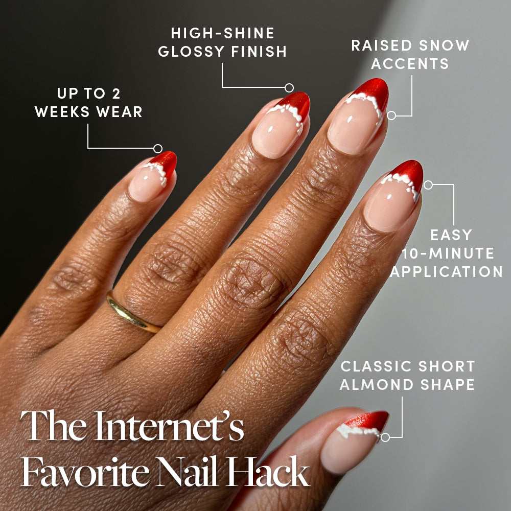 A hand displays short, almond-shaped Snow Kissed press-on nails by Glamnetic with red French tips and raised white snow accents, featuring text labels for high-shine finish, two-week wear, and quick application. - Product image