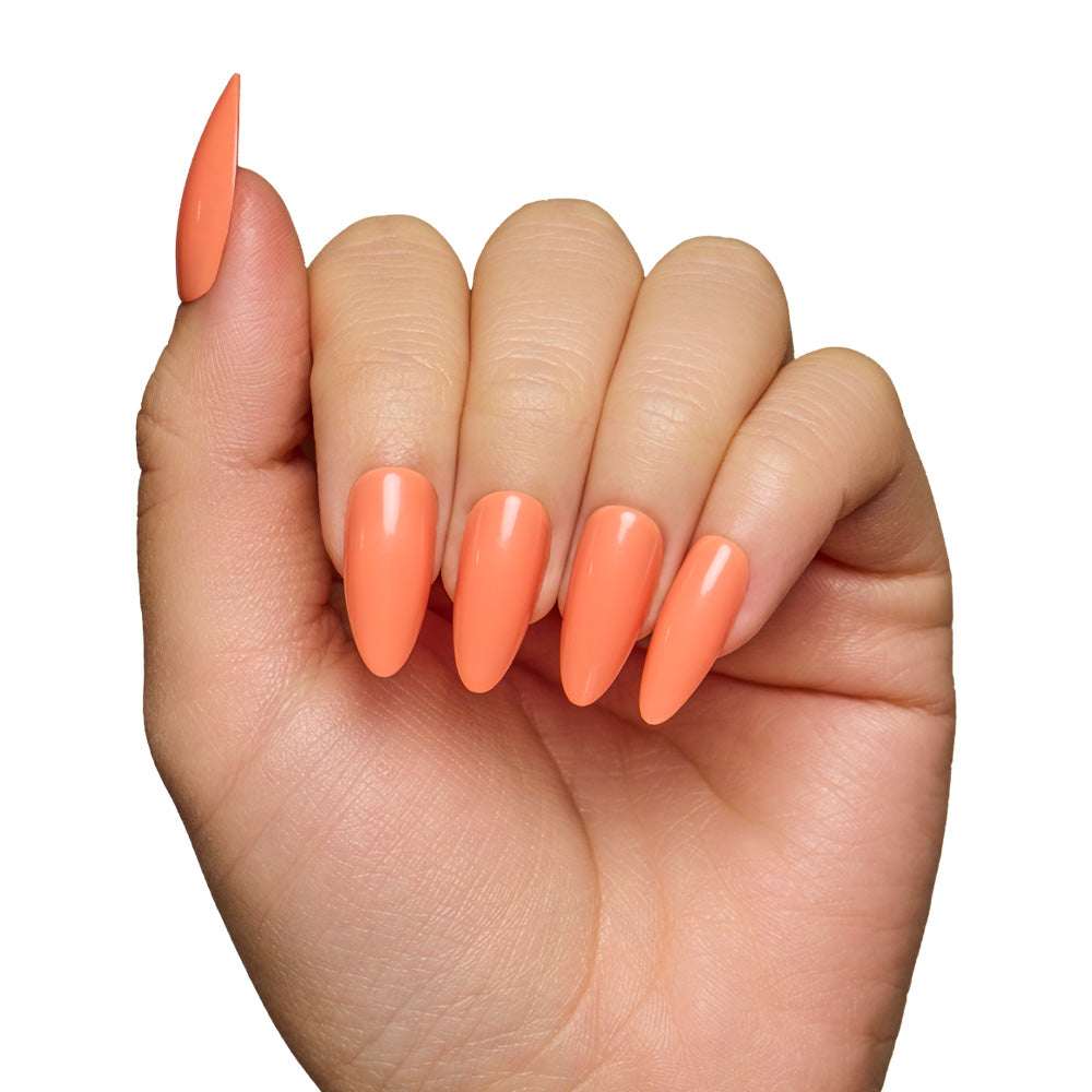 A hand with long almond-shaped nails, coated in glamnetics Soft Tangerine—a glossy pastel orange shade—stands out against a white background, highlighting the fresh elegance of this nail set. - Product image