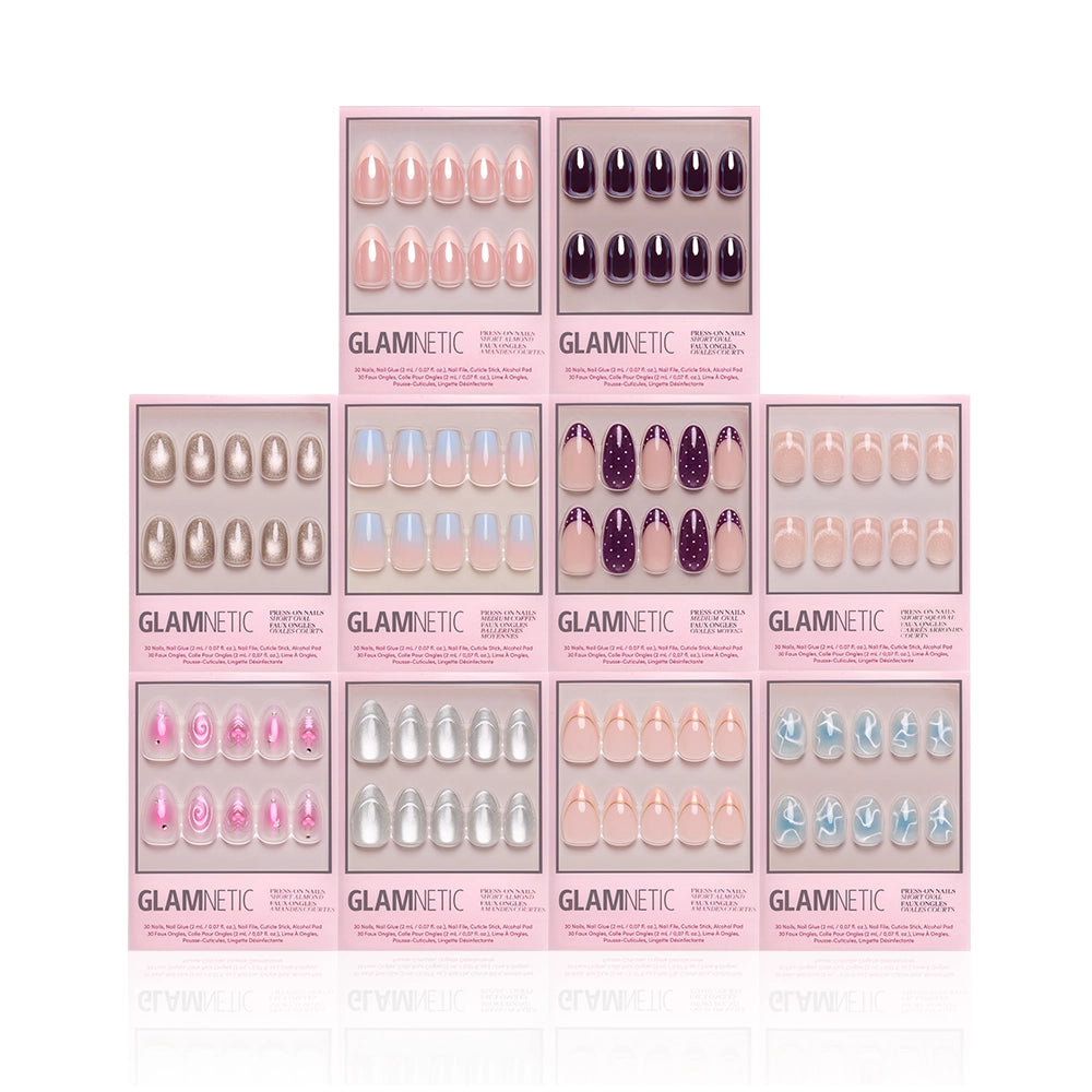 Ten boxes of glamnetic press-on nails, including the “Soft Life” set, are arranged in a pyramid shape. Each box showcases a unique nail color or design—such as soft pink from the Soft Life collection—along with purple, blue, nude, and glitter styles in various finishes and shapes for salon-quality nails at home. - Product image