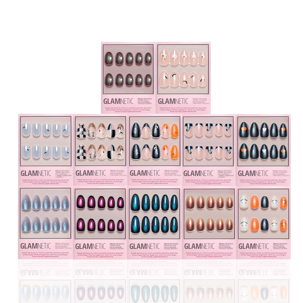 Twelve boxes of glamnetic Spells & Sparkles: The Glue-On Grimoire press-on nail sets in a variety of colors and designs are arranged in rows, with one box centered on top. Each box features pink borders and a clear window that reveals the salon-quality durability of the glue-on nails inside. - Product image