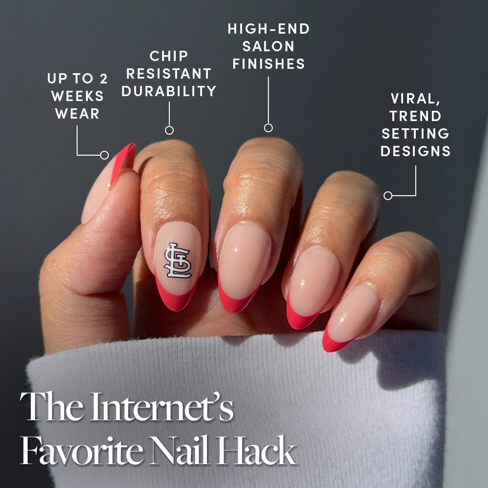 A hand with long, almond-shaped nails sports the St. Louis Cardinals Press-On Nail Set by glamnetic, featuring a pink French tip and graphic accent. Benefits: up to 2 weeks wear, chip-resistant, salon finish, and trendy designs. - Product image