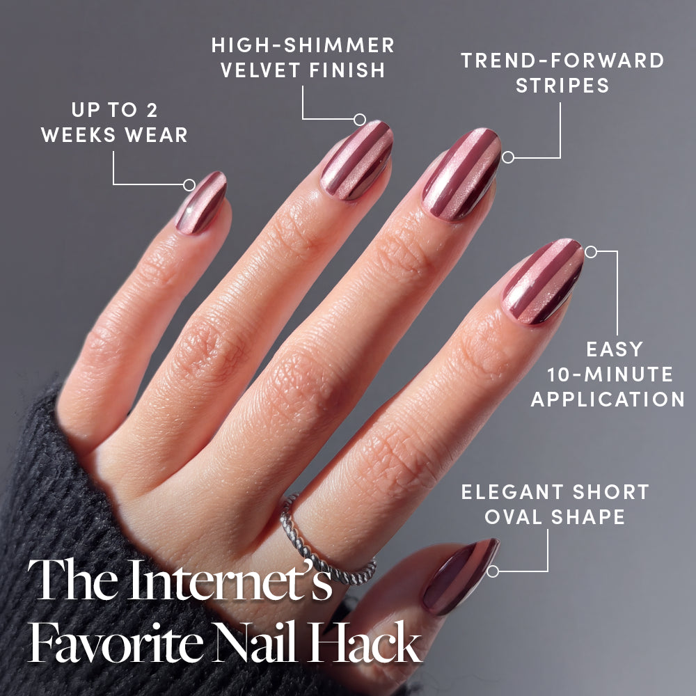 A hand displays Glamnetic Sugar Stripes short oval press-on nails with a metallic pink and brown striped velvet finish, featuring labels for their two-week wear, shimmer, striped pattern, 10-minute application, and shape. - Product image