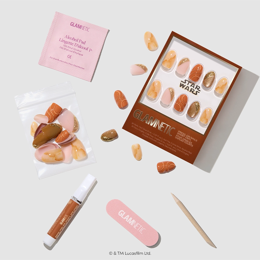 Introducing the glamnetic “Suns of Tatooine” press-on nails set, inspired by STAR WARS and Tatooine. This set features short oval nails in orange, beige, and gold shades. The Suns of Tatooine kit includes nail glue, a pink nail file, a wooden cuticle stick, an alcohol pad, and extra nail sizes—all beautifully displayed on a white surface. - Product image