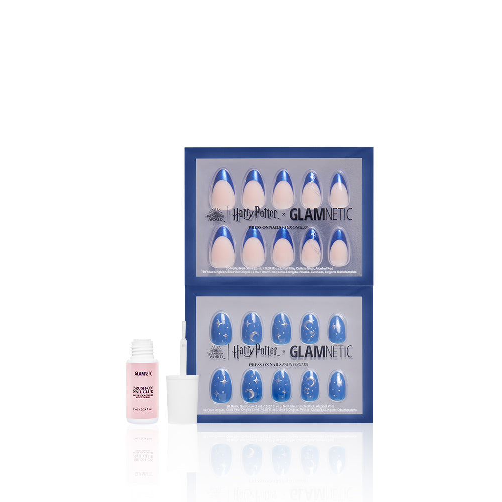 The glamnetic Team Ravenclaw™ press-on vegan nails set features blue and nude Ravenclaw-inspired nails with moon designs in two trays, alongside a small pink bottle of nail glue with an open cap and brush on a white background. - Product image