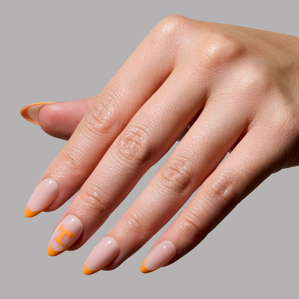 Show off your Rocky Top pride with the glamnetic Tennessee Volunteers Press-On Nail Set—almond-shaped nails with a nude base, bright orange French tips, and an accent nail featuring an orange H, set against a plain gray background. - Product image