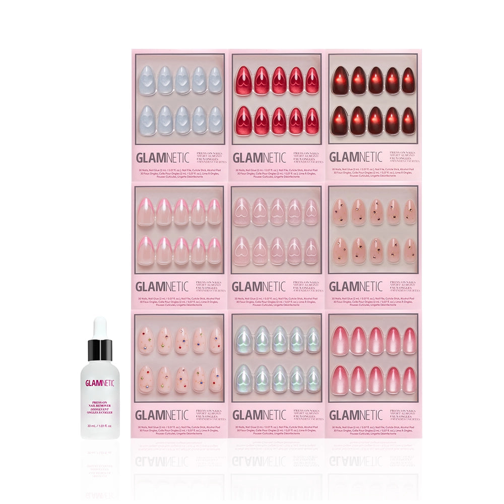 Nine boxes of glamnetic’s The Almond Vault press-on nails in assorted colors and styles are arranged in a grid above a bottle of glamnetic Nail Glue with a white dropper cap, all displayed against a white background. - Product image