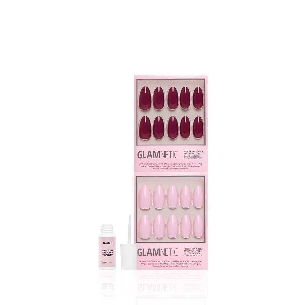 Two boxes of glamnetic press-on nails are displayed—one set is The Pink Medium Oval Icons with a glossy pink finish, and the other is dark red. An open nail glue with an applicator brush sits in front on a white background. - Product image