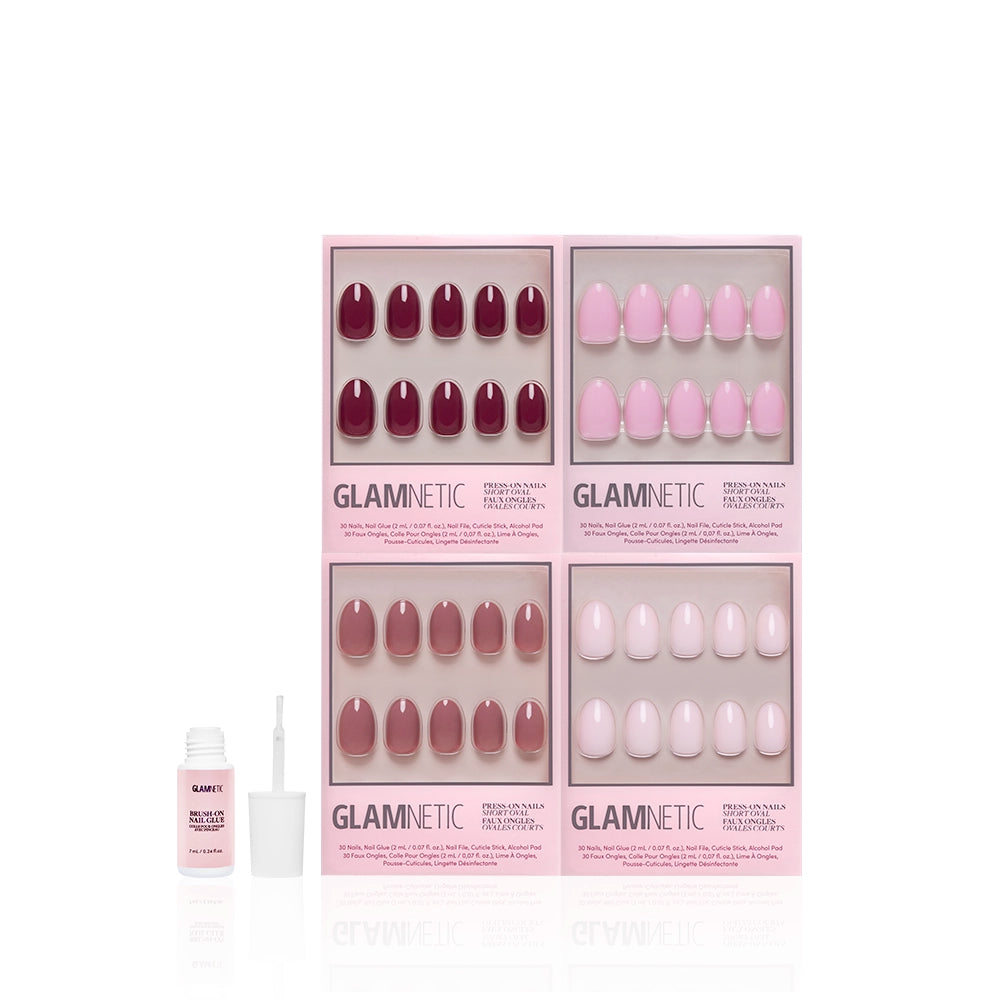 Four sets of Glamnetic The Pink Short Oval Icons press-on nails in red, pink, and nude shades are displayed in branded boxes, with a bottle of nail glue and applicator in front, all set against a white background. - Product image