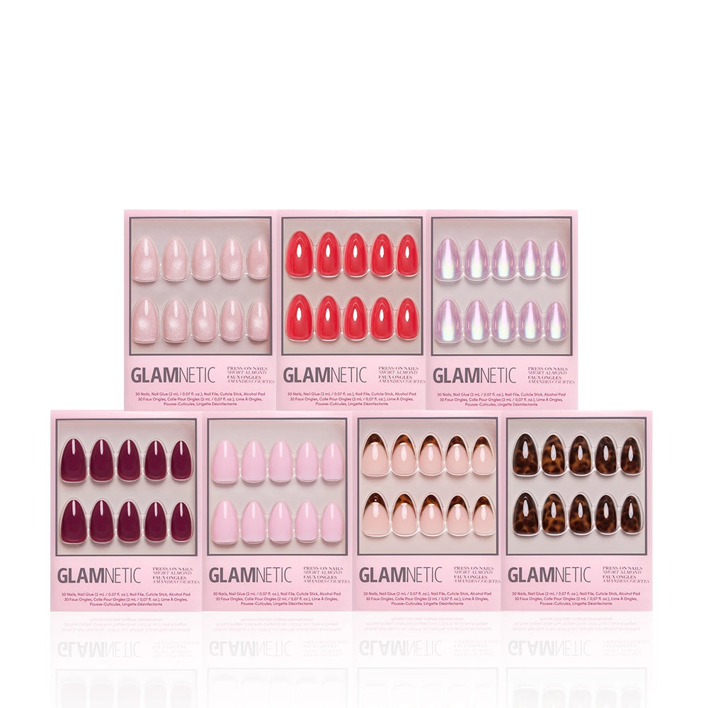 Seven sets of glamnetic The Short Almond Edit press-on nails, in pink, red, nude, and brown hues, are displayed in pink packaging against a white background. This bundle offers chic short almond nails for salon-quality manicures at home. - Product image