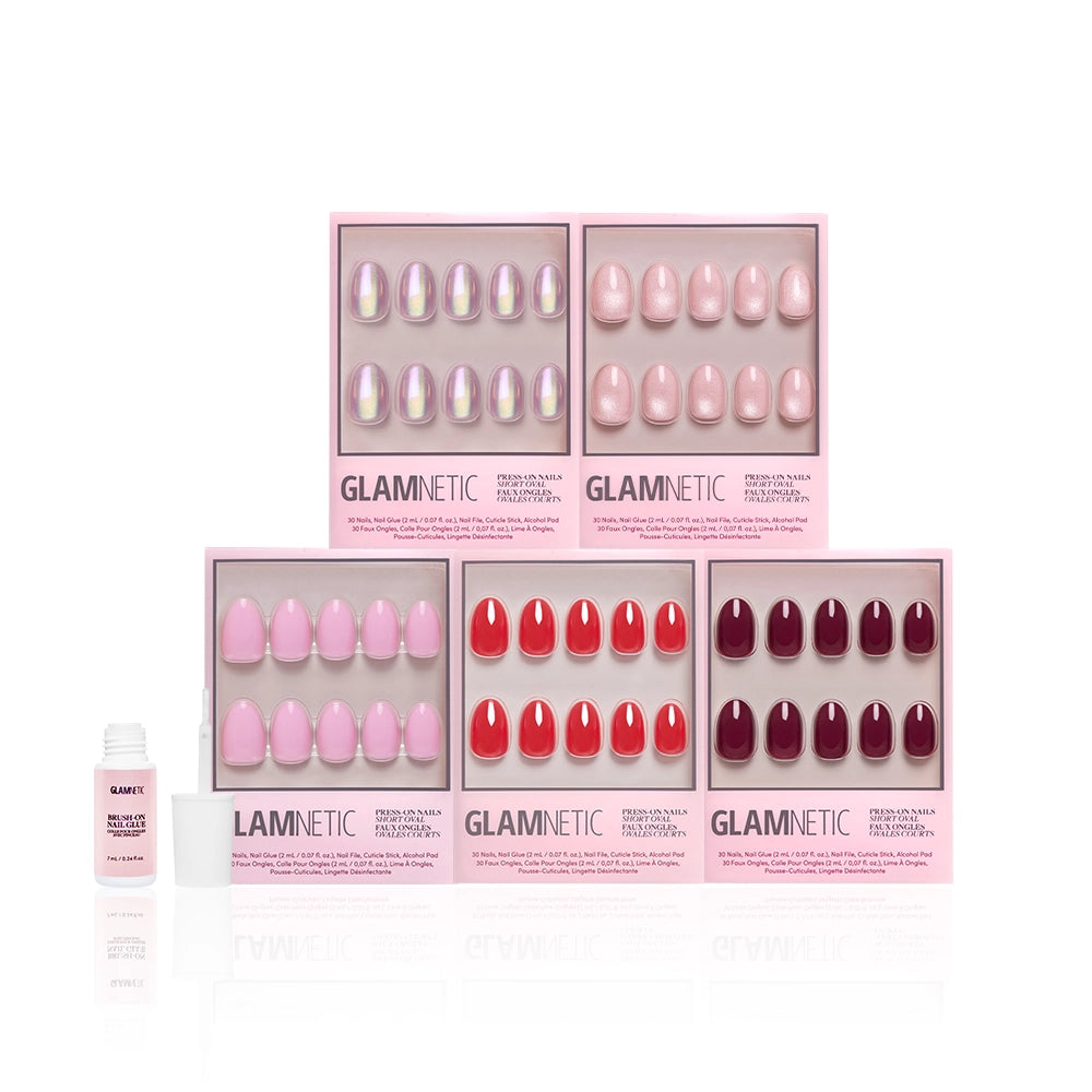 Glamnetic’s The Short Oval Edit features six press-on nail sets in pink and red, neatly arranged in pink boxes with nail glue on the left, creating a chic mani collection against a white background. - Product image