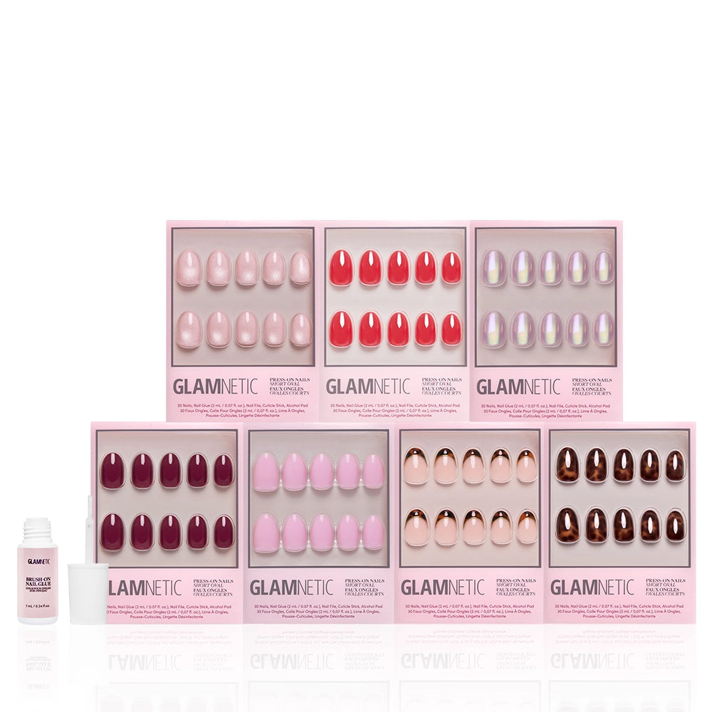 Seven boxes of glamnetic’s The Short Oval Edit press-on nails in pink, red, and neutral shades are arranged in two rows, with a small bottle of nail glue on the left—perfect for completing your mani bundle. - Product image