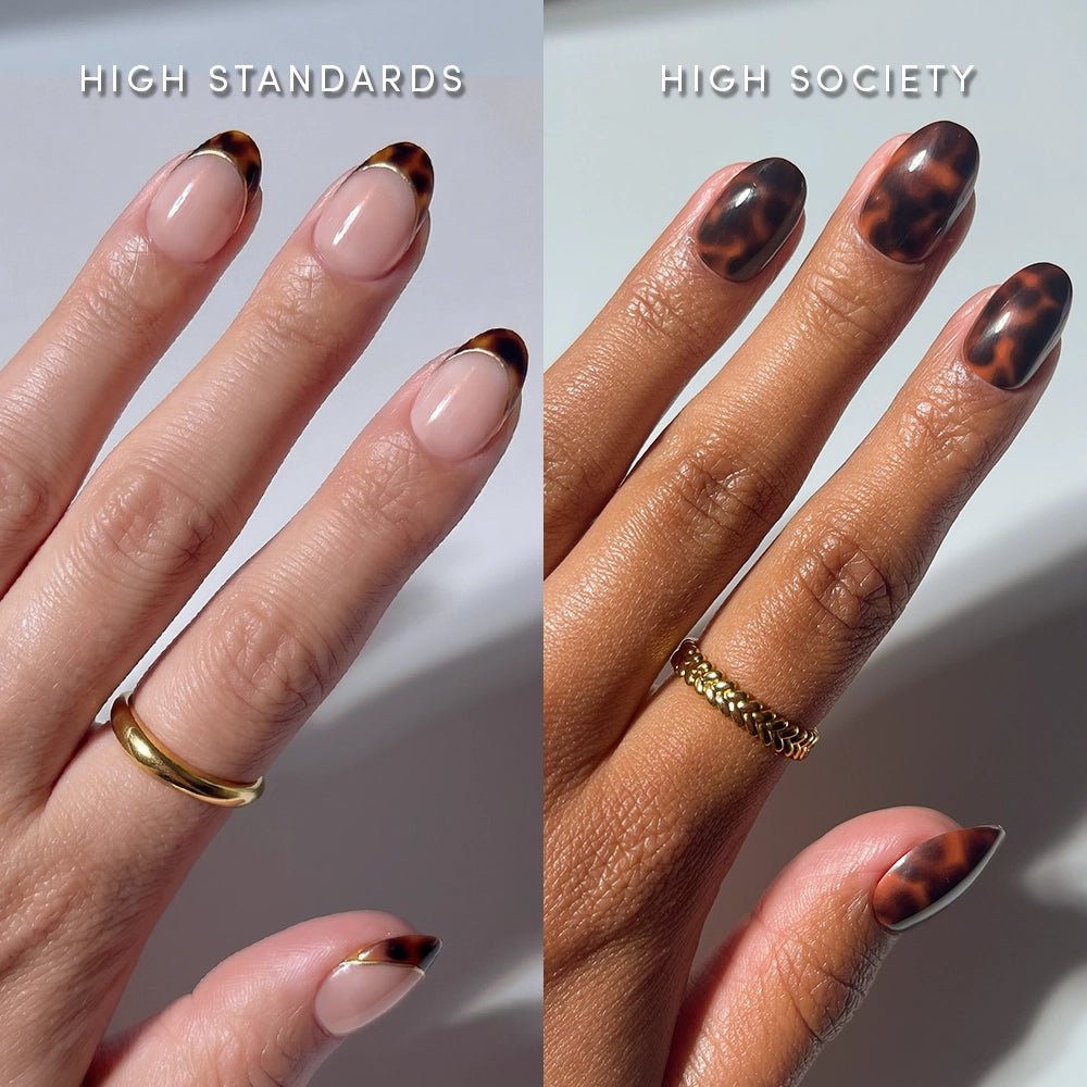 Two hands with manicured nails: the left wears a gold band ring and glossy tortoiseshell French tip press-ons; the right, a chain ring and full tortoiseshell almond nails—both styled with The Short Oval Tortoiseshell Duo by glamnetic. Text reads HIGH STANDARDS, HIGH SOCIETY.