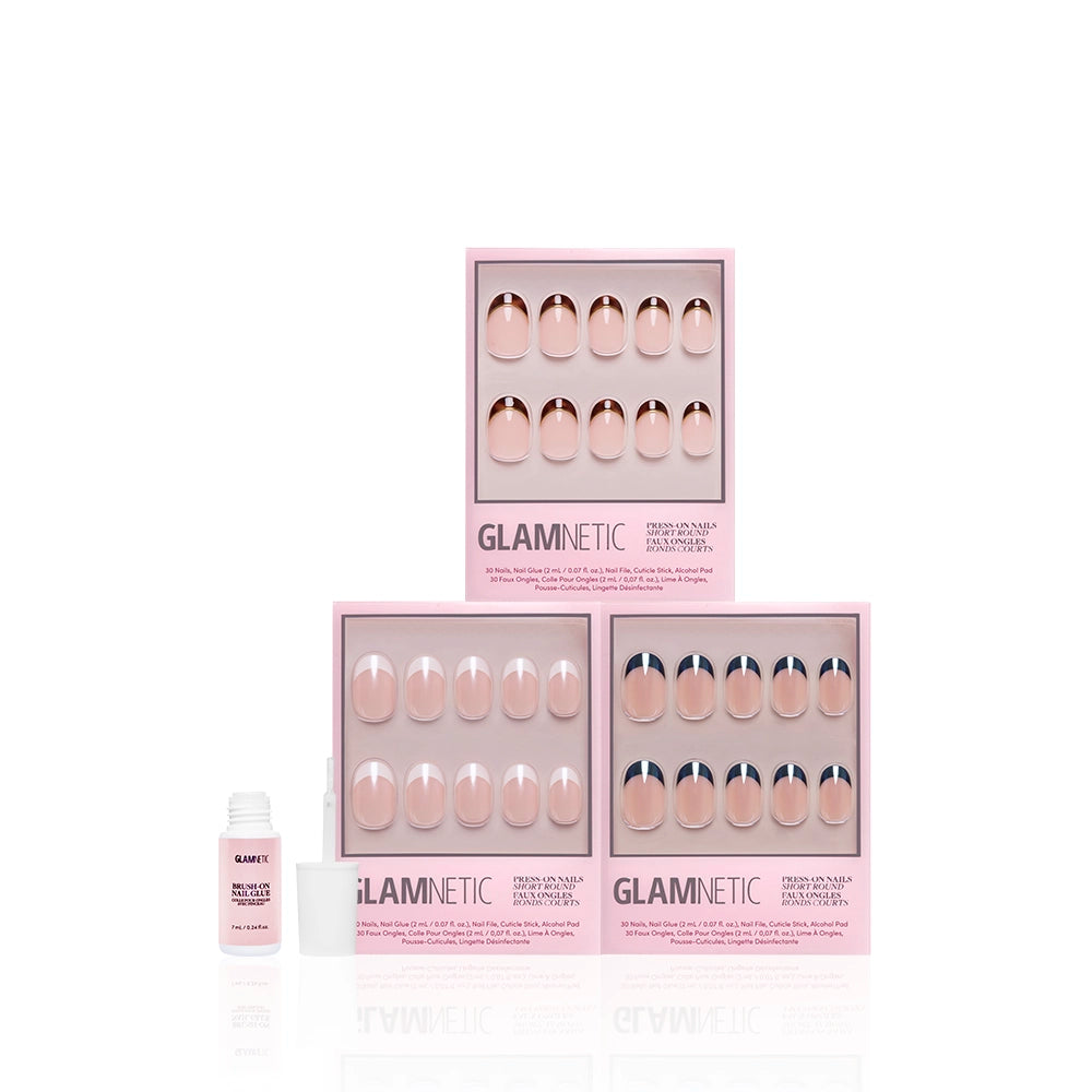 Three pink boxes of glamnetic’s The Short Round Frenchies press-on nails are stacked with an open nail glue bottle in front. These short, round nails have a glossy nude shade and subtle French tips for an elegant look. - Product image
