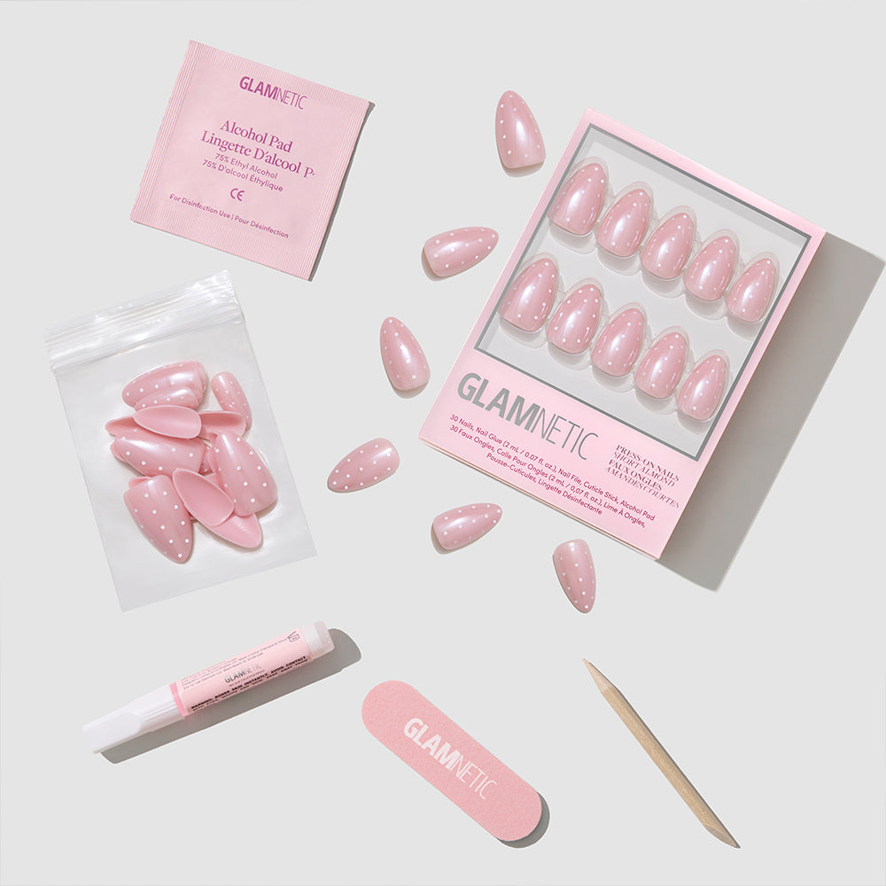 The glamnetic Barely Spotted set features short almond pink polka dot nails with extra nails, an alcohol pad, pink nail glue, nail file, and cuticle stick, all arranged on a light background. - Product image