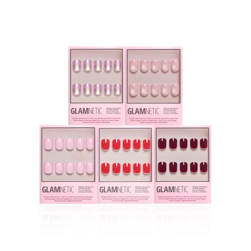 Five sets from glamnetic's The Super Short Edit are displayed in pink boxes, showcasing shades from light pink and iridescent to vibrant red and deep burgundy—all arranged neatly on a white background.