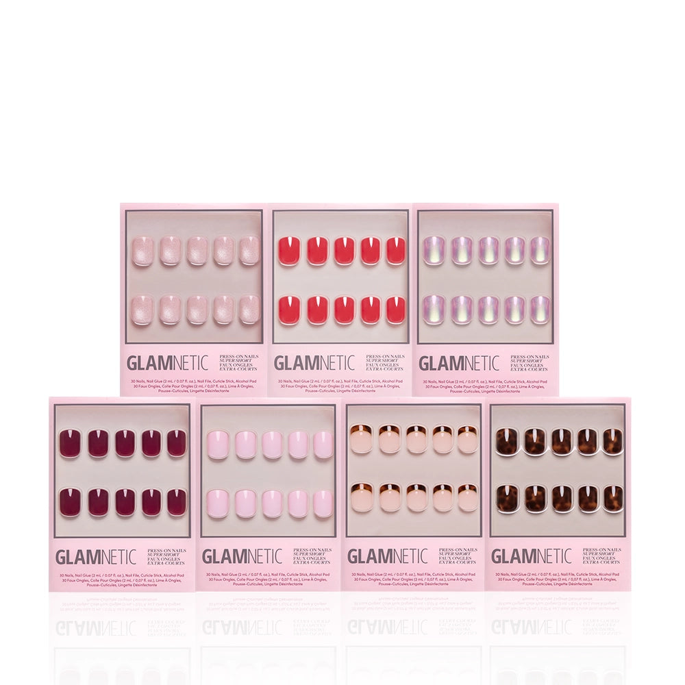Seven boxes of glamnetic’s The Super Short Edit press-on nails are displayed, each featuring a unique color or design—pink, red, nude, maroon, and iridescent—in sleek pink packaging. Ideal for creating your perfect nail bundle. - Product image