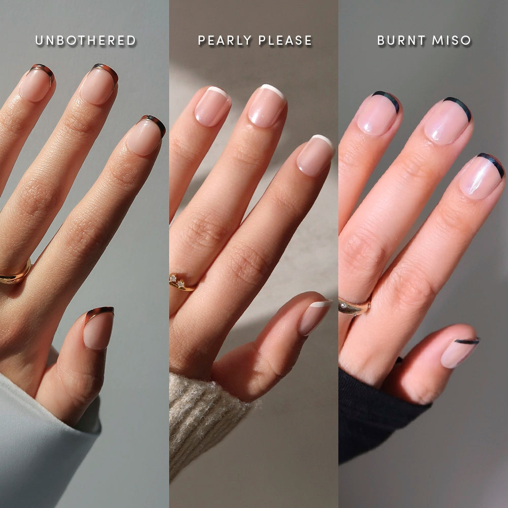 Three ring-adorned hands flaunt glamnetic's The Super Short Frenchies: left in Unbothered (thin black tips), center in Pearly Please (classic white), and right in Burnt Miso (deep brown)—all for a chic, effortless look.