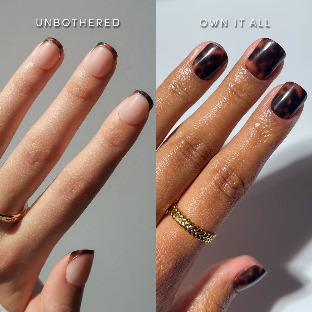 Two hands with manicured nails: the left displays light pink French tip press-ons labeled “UNBOTHERED”; the right features glamnetic’s The Super Short Tortoiseshell Duo and gold rings.