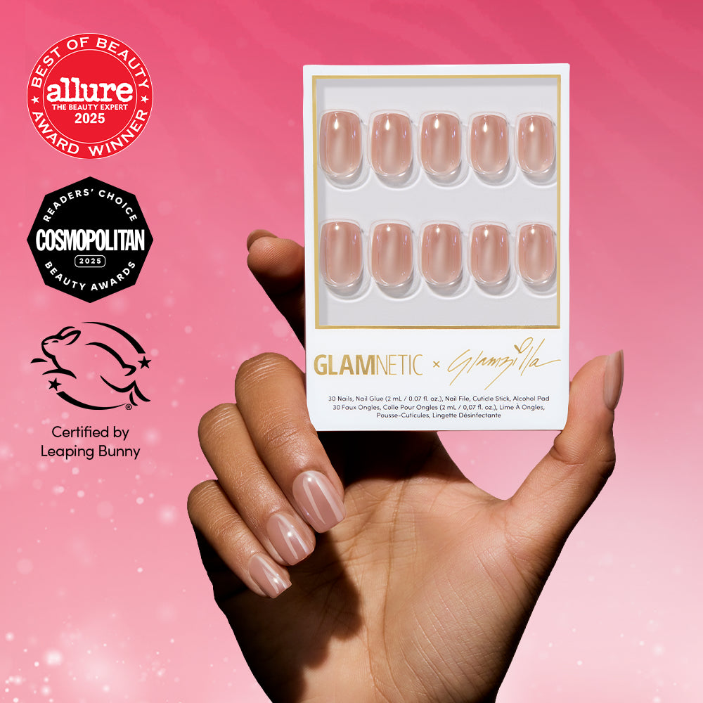 A hand with glossy nude THRILLA IN MANILA press-on nails by glamnetic holds the nail kit against a pink gradient background. Beauty award logos and a Leaping Bunny cruelty-free certification appear on the left.