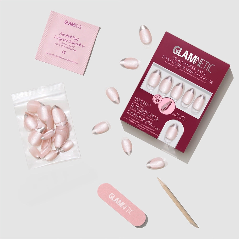 A set of glamnetic Velvet Chrome press-on nails in pink, with nail glue, cuticle stick, nail file, alcohol pad, and extra nails—all neatly arranged on a light gray surface. - Product image