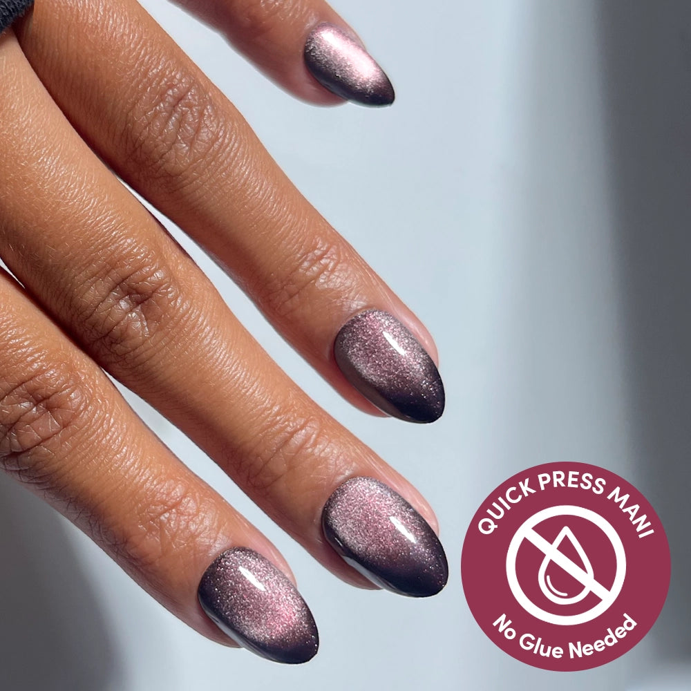 A hand with almond-shaped, shimmery pink to dark ombre press-on nails. A circular badge reads Quick Press Mani, No Glue Needed—enjoy flawless no-glue nails for salon results in seconds.