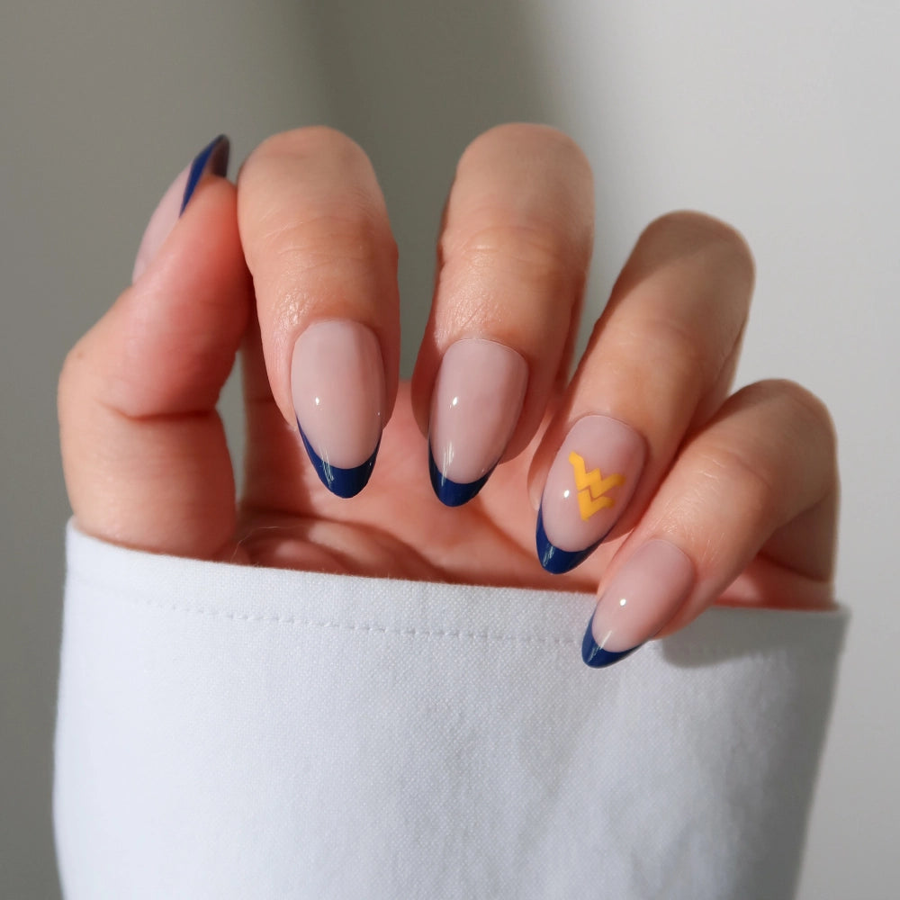 A hand wears the glamnetic West Virginia Mountaineers Press-On Nail Set—almond-shaped with a nude base, dark blue French tips, and a yellow zigzag on the ring finger. Paired with a white long-sleeve top for subtle team spirit. - Product image