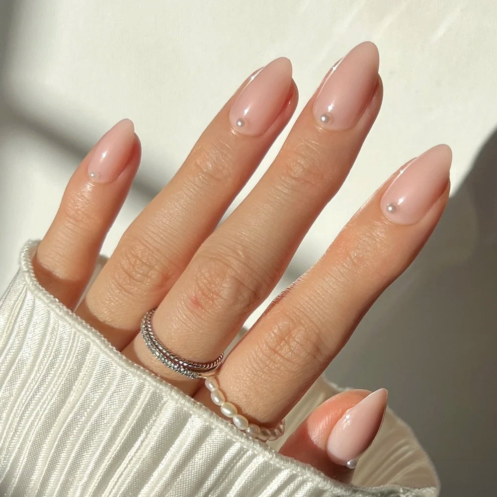 Glamnetic Wifey almond-shaped nail set featuring sheer nude polish, each accented with a single small pearl at the base for a bridal look.