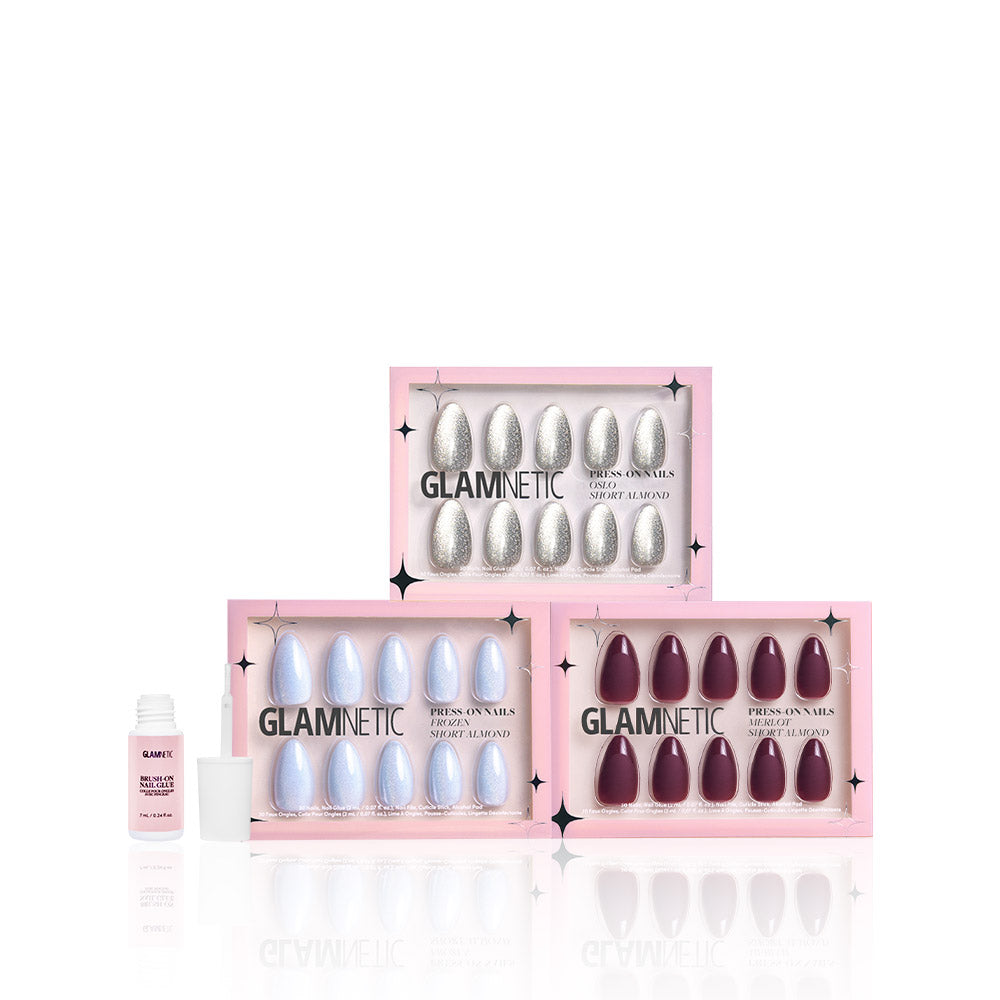 Three boxes of glamnetic’s Winter Wonderglam reusable nails—silver glitter, iridescent white, and burgundy cat’s-eye—are stacked with a nail glue bottle beside them, all displayed on a white background. - Product image
