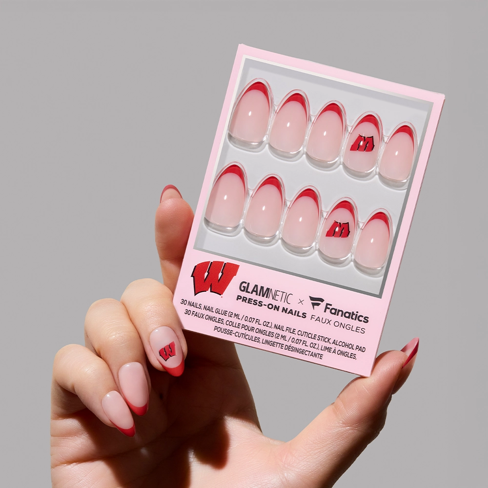 A hand with pink and red short almond nails holds the glamnetic Wisconsin Badgers Press-On Nail Set, featuring a red outline and the team’s “W” logo. The packaging reads “GLAMNETIC x Fanatics Press-On Nails.”. - Product image