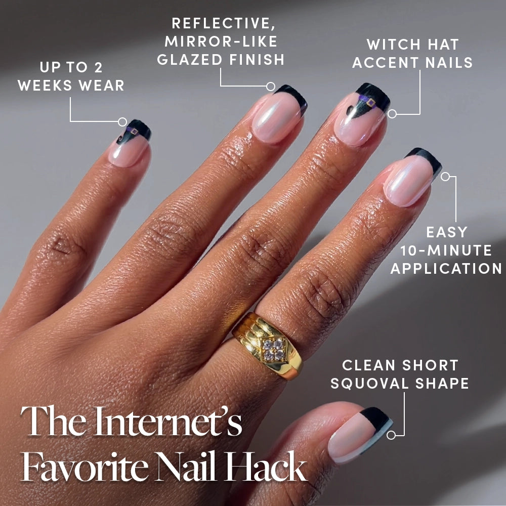A hand shows off Short Squoval Nails from glamnetic’s Witchy Woman set, featuring glossy black French tips and tiny hat accents. Text calls out up to two-week wear, an easy 10-minute application, a squoval shape, and a high-shine finish—ideal for anyone seeking stylish press-on nails. - Product image