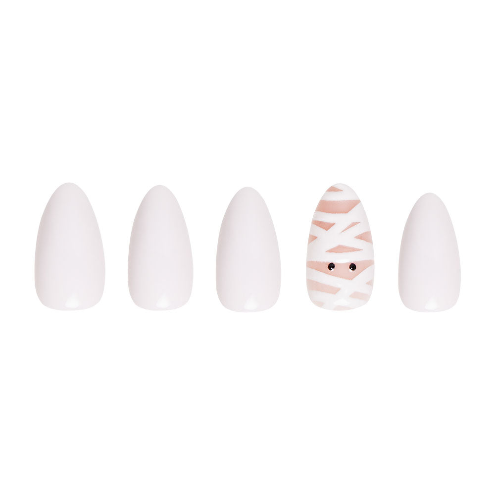 The glamnetic Wrapped Up set includes five short almond nails: four are plain white, while the fifth features a mummy face with white crisscross lines and black eyes on a nude base. - Product image