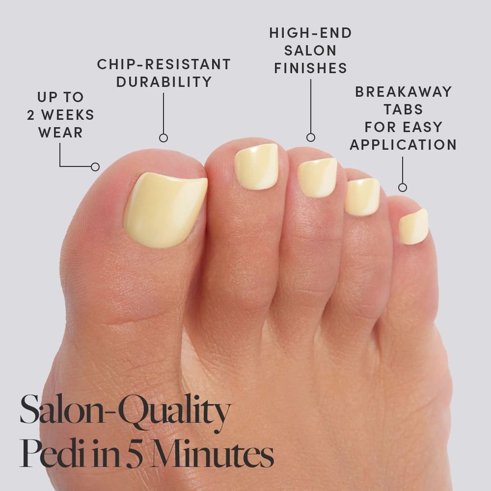 A foot wearing creamy pastel yellow shade Glamnetic press-on toenails with product features called out, including salon finish and 2-week wear. - Product image