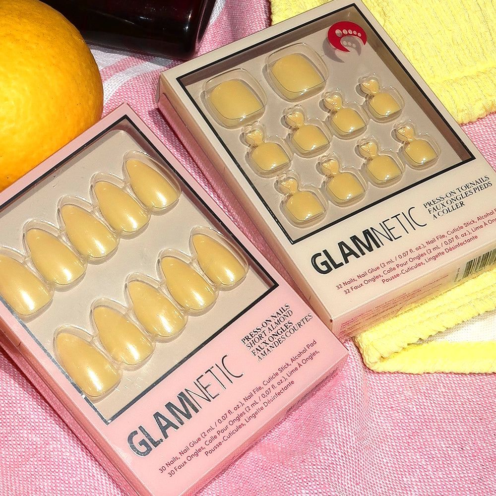 Glamnetic pastel yellow press-on nail sets in a box on a pink surface. - Product image